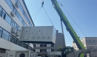 Containerized system lifted beside a building